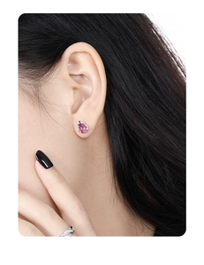 Macro shot of purple teardrop crystal earring with silver setting worn on ear