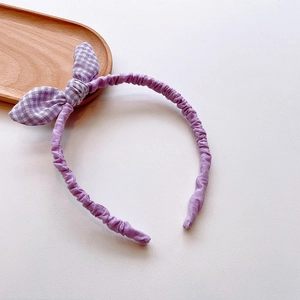 Close-up of purple ruffled fabric headband with checkered bow and soft cotton texture