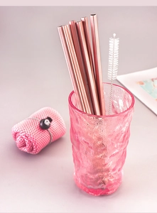 Close-up of five rose gold heart-shaped stainless steel straws and cleaning brush in a cup