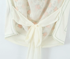 Detailed view of the back ribbon tie and floral chiffon fabric on the cream top