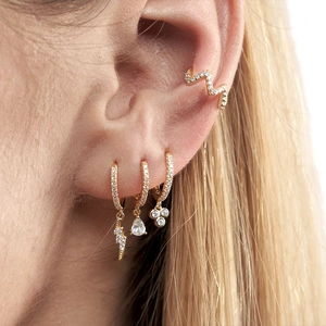Close-up of a gold geometric earring set with lightning bolts and sparkling zircon stones