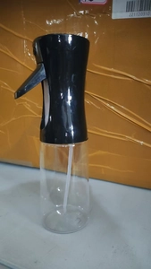 Detail view of a black spray nozzle and transparent plastic oil bottle with straw