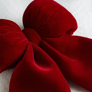 Deep red velvet Christmas bow decoration on white faux fur background for holiday decor