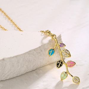 Gold leaf pendant necklace with colorful enamel and sparkling zircons on white stone