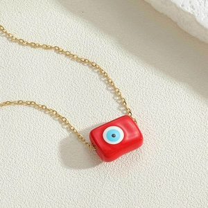 Macro shot of rectangular red evil eye pendant necklace with a delicate gold chain
