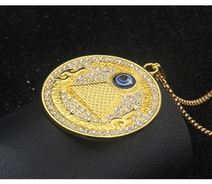 Detailed close-up of golden evil eye necklace with blue center and crystal halo