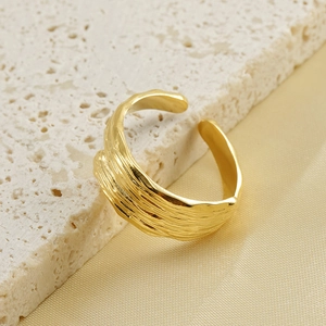 Detailed view of the 18K gold wave-textured adjustable open ring on a stone background