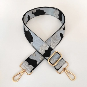 Close-up of adjustable woven camo shoulder strap with gold metal lobster clasps