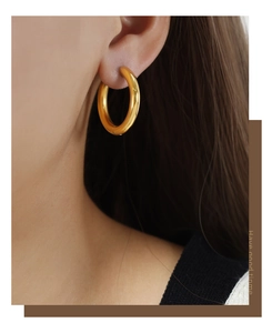 Detailed close-up of chunky 18k gold plated hoop earrings worn on the ear for a retro look