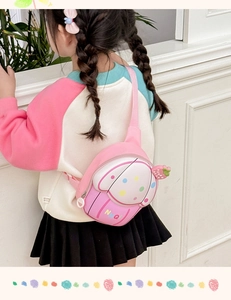 Close-up of pink cartoon kids chest bag with strawberry charm on a child's back