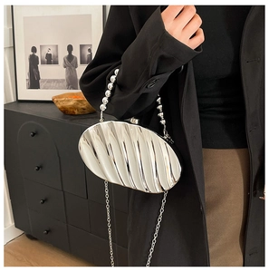 Detail of silver shell-shaped acrylic evening bag with wavy texture and beaded handle