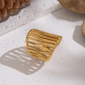 Wide geometric hollow multi-layer gold stainless steel ring on natural stone background