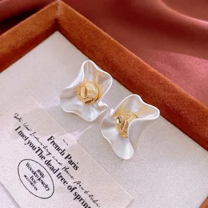 French vintage white wavy petal earrings with gold bead center on brown silk backdrop
