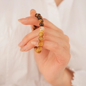 Macro detail of polished tiger eye bead bracelet with a golden floral spacer bead