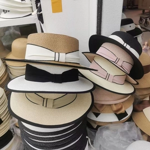 Detailed display of summer flat top straw sun hats in various colors with ribbon bows