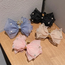 Detail view of four velvet bow hair clips with pearls and rhinestones on wood surface