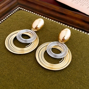 Detail of twisted gold and silver geometric earrings on green velvet tray