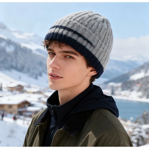 Close-up of thick knitted winter hat with grey knit texture against a snow mountain backdrop