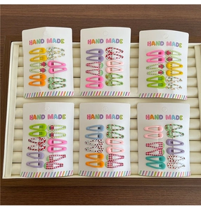 Close-up of cute fruit print and checkered BB hair clips for girls on a handmade card
