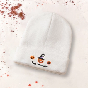 Detailed embroidery of three pumpkins and Happy Halloween text on a white knit beanie
