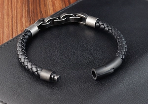 Macro detail of braided leather bracelet with magnetic metal clasp on dark background
