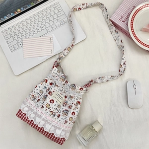 Detail of cartoon embossing on a cream crossbody bag with lace trim and heart patterns