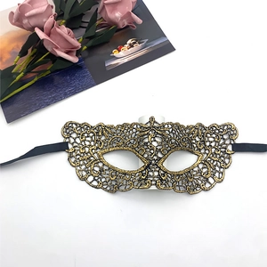 Detail of gold lace masquerade mask showing intricate hollow patterns and black ribbons