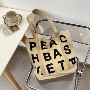 Detail of khaki canvas tote bag with black letter print on a stylish modern chair