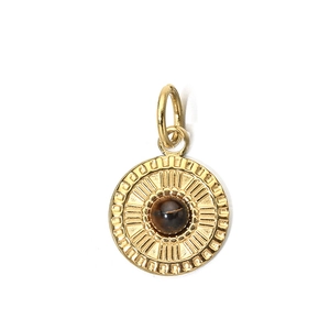 Detail of round gold stainless steel pendant with brown stone and radial textures