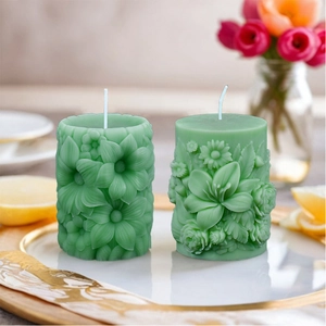 Groene cilindrische roos- en lelie-reliëfkaarsen op een elegant dienblad voor decor