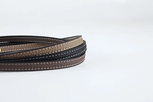 Detailed macro view of lychee pattern leather handbag straps with contrast white stitching