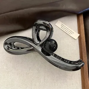 Macro d'une pince à cheveux en métal noir fusil au design torsadé et grosse boule