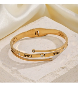 Detail of gold layered spiral bracelet with LOVE engraving and sparkling crystals