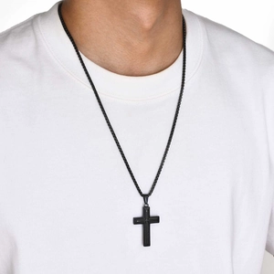 Close-up of a black textured cross pendant on a matching box chain worn by a male model