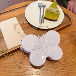 Détail du sac papillon blanc en gelée avec chaîne dorée sur table en bois