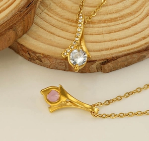 Detail view of gold pendant necklace featuring sparkling pink and clear zircon crystals