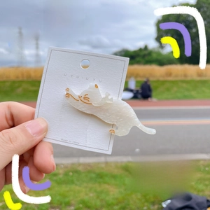 Detail showing creamy white translucent cat hair clip with gold glitter in hand