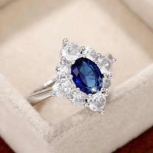 Makroaufnahme von blauem ovalem Edelsteinring mit Diamantcluster auf Samt