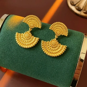 Détail de boucles d'oreilles vintage dorées en forme d'éventail texturées