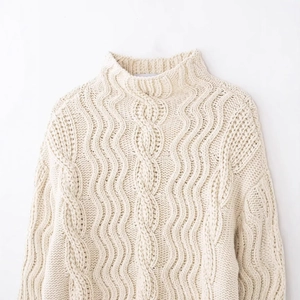 Creamy white cable knit sweater with half-high collar and Fair Isle textured patterns