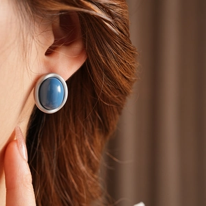 Close-up of blue and white enamel oval earrings worn by model for a vintage aesthetic