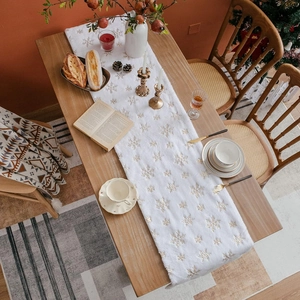 Detailed top view of white plush Christmas table runner with golden snowflake patterns