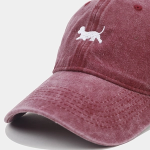 Macro del ricamo cucciolo bianco e cuciture su cappello da baseball bordeaux lavato