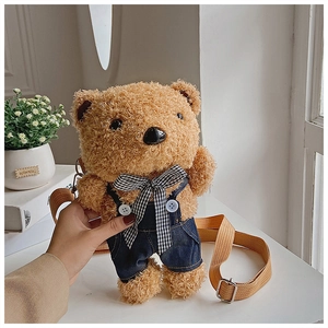 Close-up of plush bear bag wearing denim overalls with adjustable shoulder strap details
