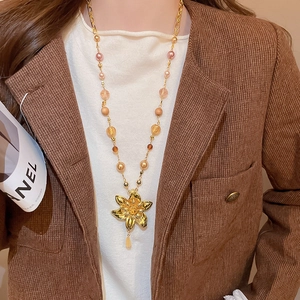 Détail d'un sautoir à pendentif floral avec perles colorées porté par un mannequin