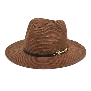 Detailed texture of dark brown straw sun hat with black leather band and gold buckle