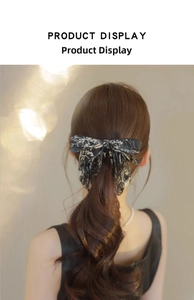 Close-up of ink-wash floral bow hair clip on a low ponytail with silky texture ribbons