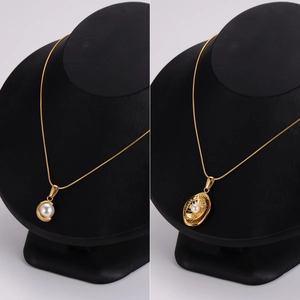 Colliers vintage français en or avec pendentifs en perles sur des présentoirs noirs élégants