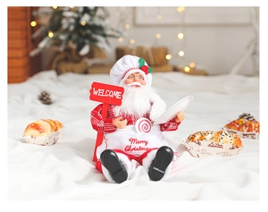 Detail of chef Santa doll holding a Welcome sign with Merry Christmas apron embroidery