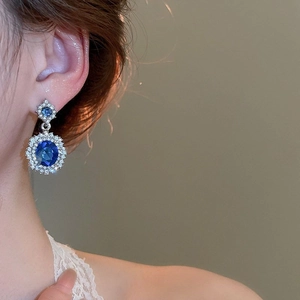 Detail of sapphire blue drop earrings with halo diamond setting on a silver base